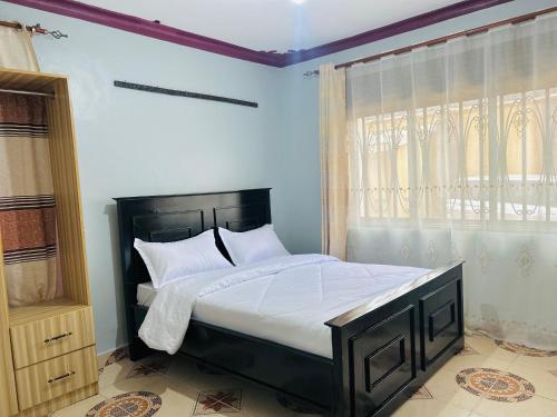 a bedroom with a large bed with white sheets and a window at Zarex homes 1 in Mbale
