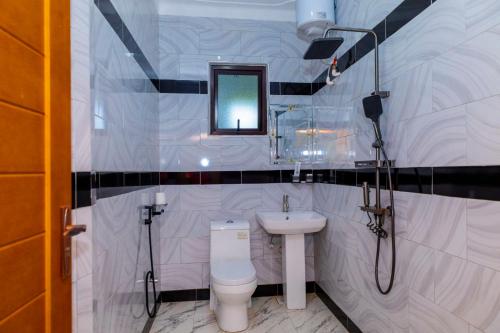 a white bathroom with a toilet and a sink at Hotel Amani Limited in Mwana Island
