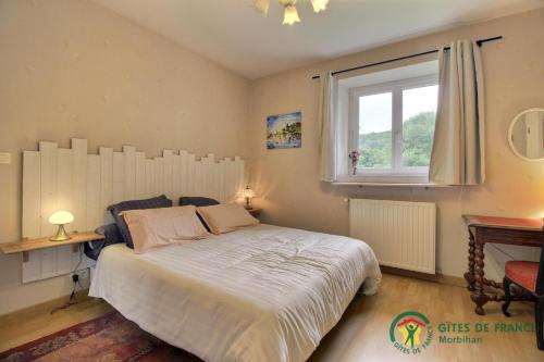 a bedroom with a large bed and a window at Le Manoir de Gourvinec in Saint-Nolff