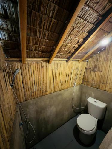 a bathroom with a toilet in a room with wooden walls at Kampa Lodge in Tano