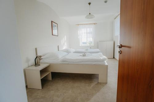 a white bedroom with a white bed and a window at Penzion Albertovec in Opava