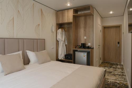 a bedroom with a large white bed and a robe at Solara in Bishkek