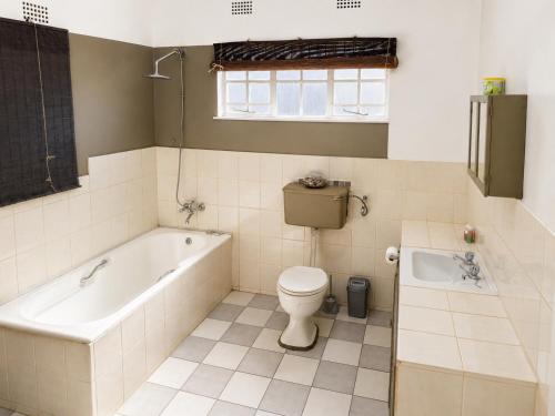 a bathroom with a tub and a toilet and a sink at Nut Tree Nook in Hazyview