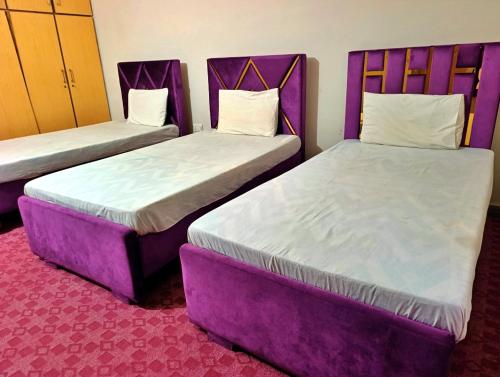 two beds in a hotel room with purple furniture at Eden Plus Executive Hotel Lahore in Lahore