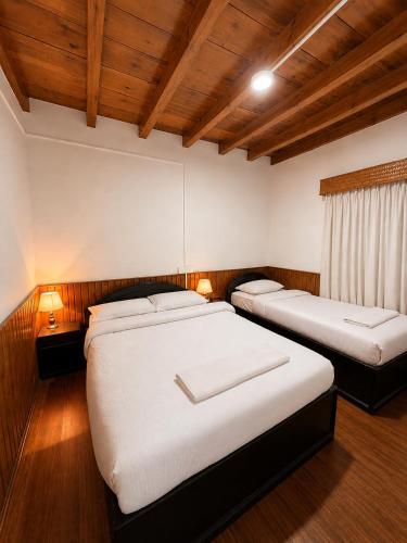 two beds in a room with wooden floors and ceilings at Xanadu Homes in Jomsom