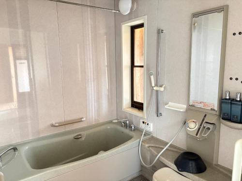 a bathroom with a green bath tub and a window at Yamaneko Lodge in Gujo