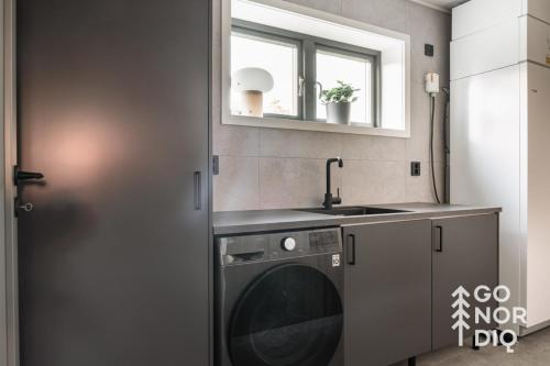 a kitchen with a washing machine and a sink at Black Grouse Lodge in Tällberg