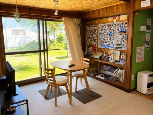 a table and chairs in a room with a window at ゲストハウス潮目 in Shibetsu