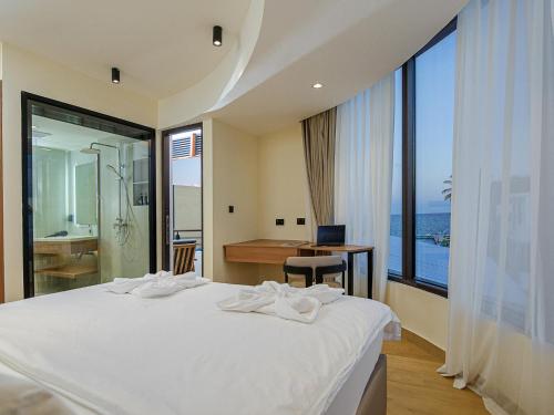 a bedroom with a bed and a desk and a large window at Kinan Sentral in Fulidhoo