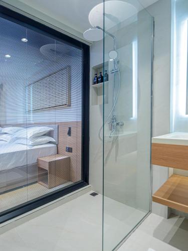 a bathroom with a glass shower and a bed at Kinan Sentral in Fulidhoo