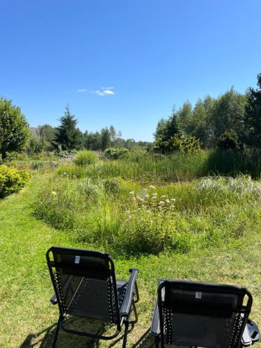 two chairs sitting in the grass near a field at Pensjonat i domki Kresy in Pogorzelce