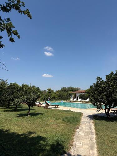 a swimming pool in a park with trees and a path at Masseria Incantalupi in San Vito dei Normanni