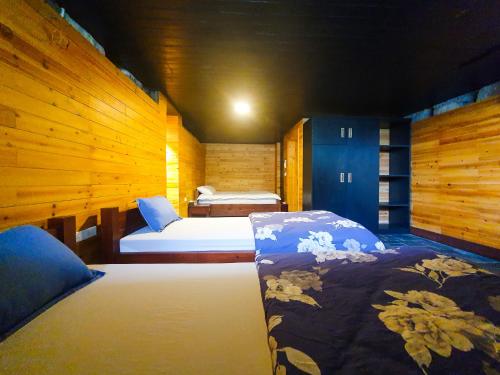 two beds in a room with wooden walls at Phủ Homestay Sapa in Sapa