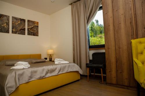a bedroom with a bed and a window and a chair at Sungora sun&ski resort in Slavske