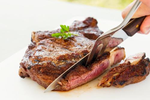 a person cutting a piece of steak with a knife at Ibis Hotel Alicante in Alicante