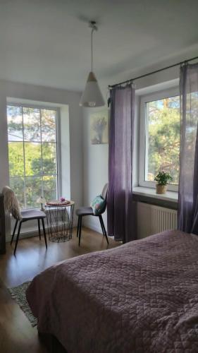 a bedroom with a bed and a window with purple curtains at Willa Myśliwska Giżycko in Giżycko