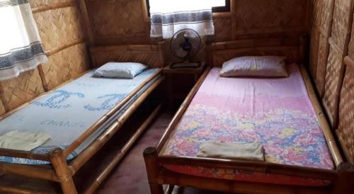 two twin beds in a room with a window at calayo beach resort in Calayo