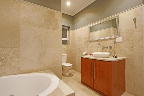 a bathroom with a tub and a sink and a toilet at Bed and Breakfast Villa de la Mer in Hout Bay