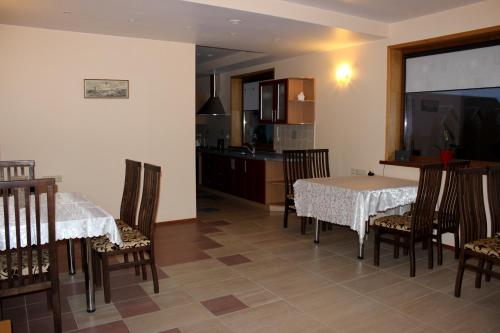 una sala da pranzo con due tavoli e sedie e una cucina di Vidų Guest House a Utena