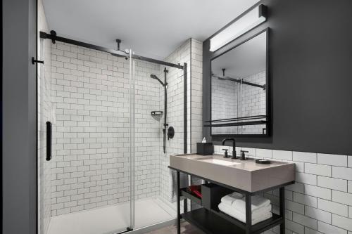 a bathroom with a sink and a shower with a mirror at New Moxy Ottawa Downtown in Ottawa
