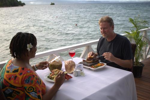 a man and a woman sitting at a table with food and wine at Rapopo Plantation Resort in Kokopo