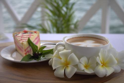 a cup of coffee and a piece of cake and flowers at Rapopo Plantation Resort in Kokopo