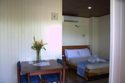 a bedroom with a bed and a table with a vase on it at Rapopo Plantation Resort in Kokopo