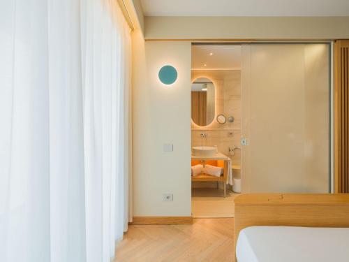 a bedroom with a glass door leading to a bathroom at San Vito Resort & Spa in San Vito lo Capo