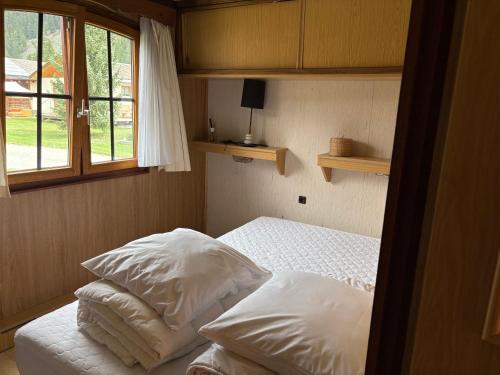 a bedroom with two beds with white pillows and a window at Mobile home Le paradis dans la nature in Bourg-Saint-Pierre
