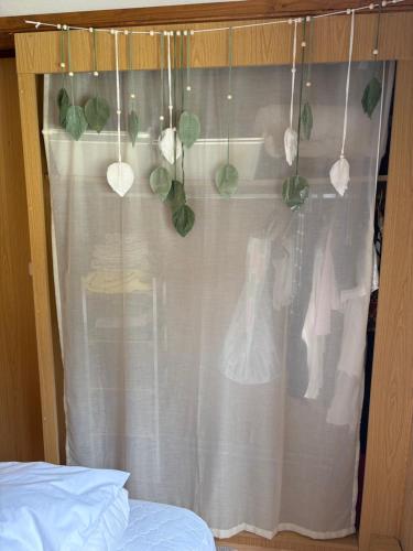 a bedroom window with a white curtain with green leaves at Mobile home Le paradis dans la nature in Bourg-Saint-Pierre