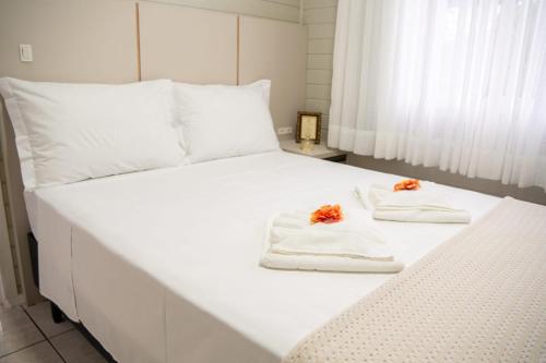a white bed with towels and flowers on it at Sítio Monte Frederico in Nova Trento