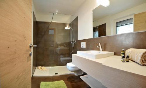 ein Badezimmer mit einem Waschbecken, einem WC und einem Spiegel in der Unterkunft Landhaus Freiburgerhof in Riffian