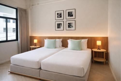 a bedroom with two white beds and two lamps at Into the town krabi in Krabi