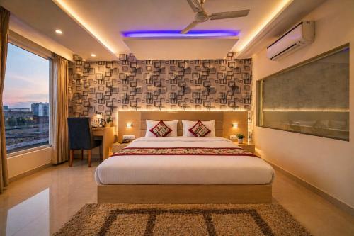 a bedroom with a bed and a desk and a window at Hotel Ronit Royal - Delhi Airport in New Delhi