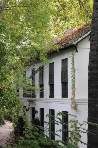 an old white house with black windows and trees at Hotel del Balneario in Tolox