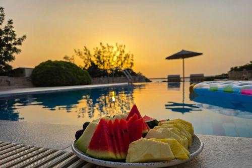 a plate of fruit on a table next to a pool at Bliss House Villa in Plaka