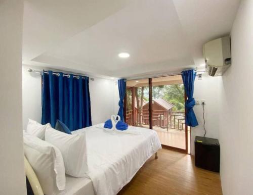 a bedroom with a white bed and blue curtains at Europe Enchanted Resort in Kaôh Rŭng (3)