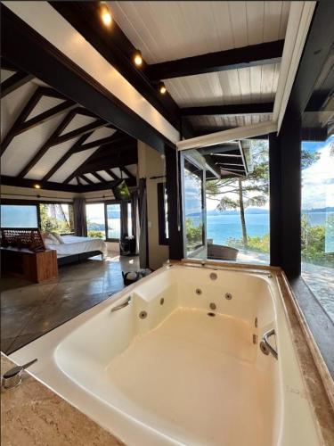 a large white bath tub in a room with windows at Resort Refúgio do Estaleiro in Porto Belo