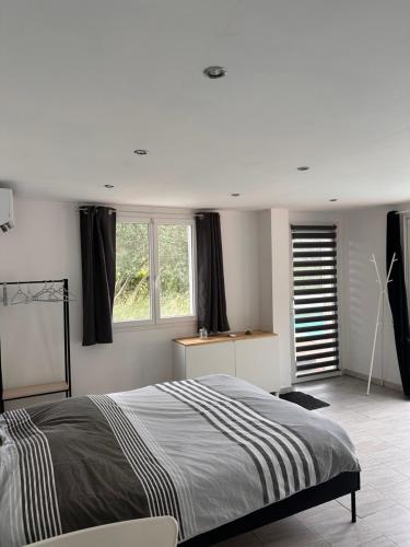 a bedroom with a large bed and two windows at Dépendance climatisée au sud de Toulouse in Lacroix-Falgarde