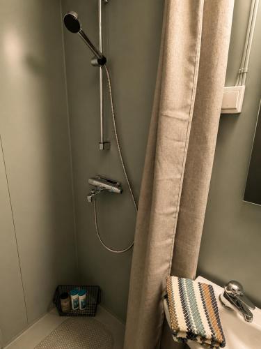 a shower with a shower curtain next to a sink at Linken Studio for 2 in Narvik