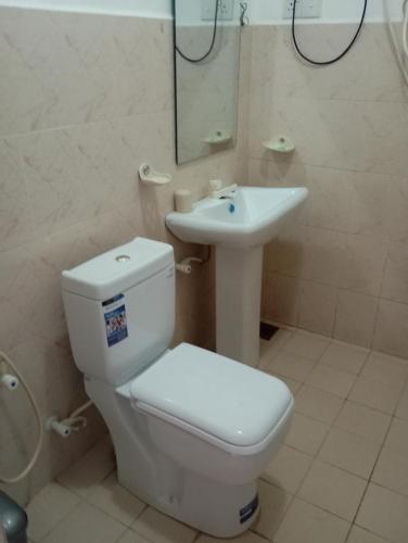 a bathroom with a white toilet and a sink at Larn's Villa Hotel & Apartment in Wadduwa