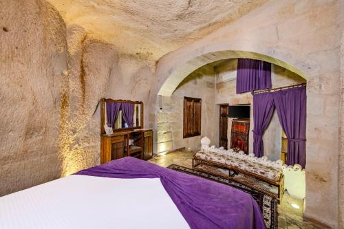 a bedroom with a large bed and purple curtains at Hidden Cave Hotel in Göreme