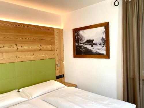 a bedroom with a bed and a picture on the wall at Garnì Stella Alpina in Canazei