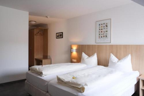 a hotel room with two beds with white sheets at Hotel Garni Brugger in Lindau
