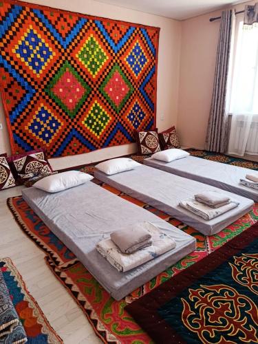 two beds in a room with a colorful wall at SunLake House in Balykchy