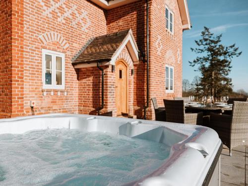 a large hot tub in front of a brick building at Copper Beech Cottage in Welshpool