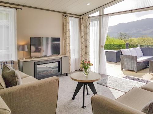 a living room with a fireplace and a television at Ben Vorlich Lodge in Saint Fillans