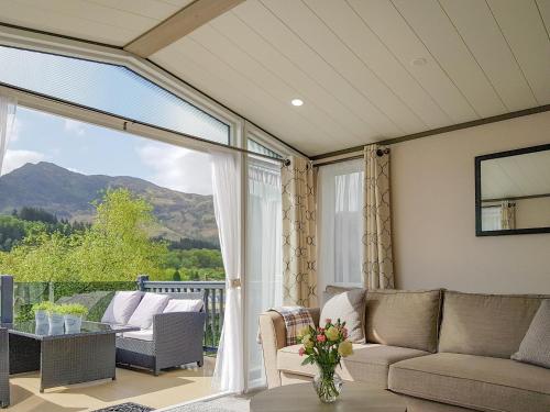 a screened in porch with a couch and a table at Ben Vorlich Lodge in Saint Fillans