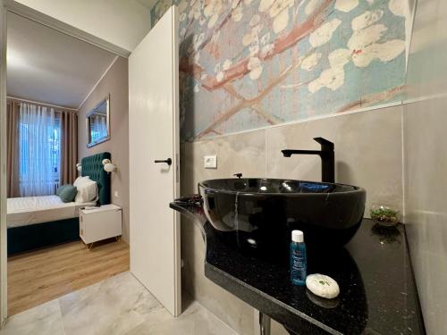 a bathroom with a black sink and a bedroom at Duomo Next Accomodations in Trento