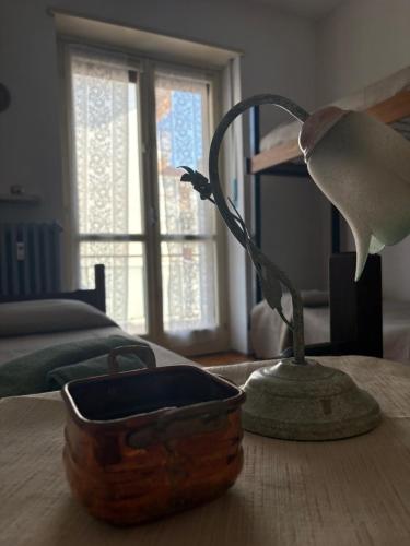 a lamp sitting on a table next to a bed at Rifugio Delia in Torre Pellice
